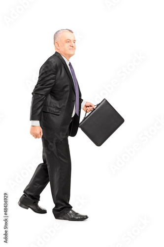 Photo: Full length portrait of a mature businessperson briefcase walkin Full length portrait of a mature businessperson briefcase walkin