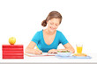 Teenage girl writing homework and having a meal