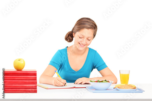Photo: Teenage girl writing homework and having a meal Teenage girl writing homework and having a meal