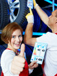 Apprentice for car mechanic shows thumb up for tire label