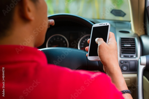 Photo: Asian man texting while driving Asian man texting while driving