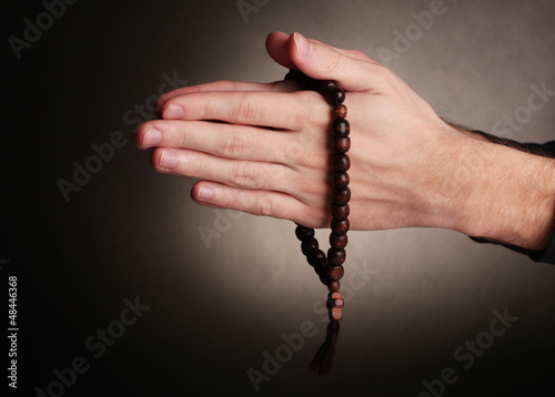 Photo: Hands holding wooden rosary on grey background Hands holding wooden rosary on grey background