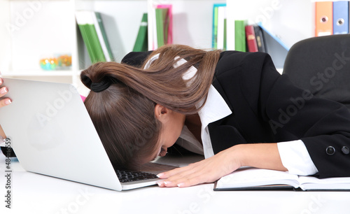 Photo: Tired business woman with notebook in her workplace Tired business woman with notebook in her workplace