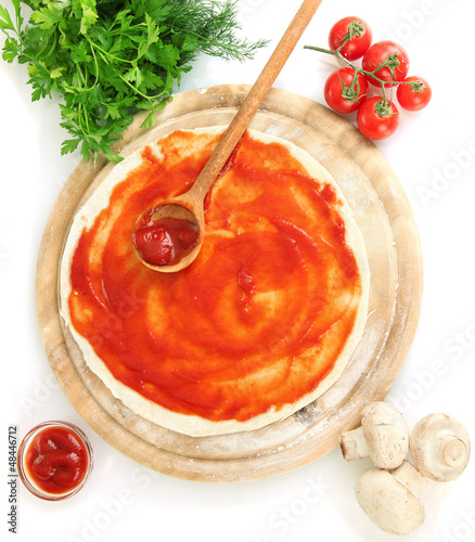 Photo: Pizza dough with tomato sauce on wooden board isolated on white Pizza dough with tomato sauce on wooden board isolated on white
