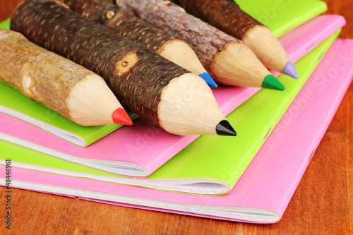 Photo: Colorful wooden pencils with exercisebooks on wooden table Colorful wooden pencils with exercisebooks on wooden table