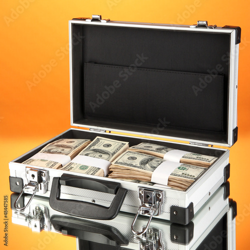 Photo: Suitcase with 100 dollar bills on orange background Suitcase with 100 dollar bills on orange background