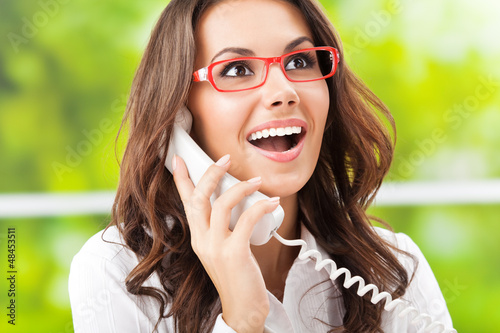 Photo: Young woman with phone, at office Young woman with phone, at office