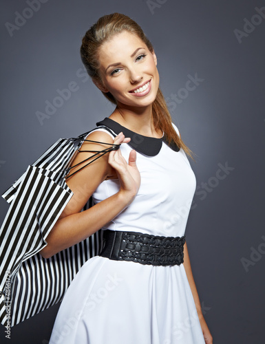 Photo: Shopping woman holding bags, isolated on gray studio background. Shopping woman holding bags, isolated on gray studio background.