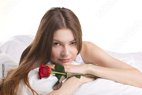 Photo: beautiful woman with rose in a bed beautiful woman with rose in a bed