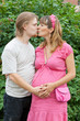 a happy young pregnant woman kisses her husband