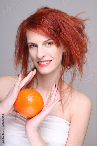 Photo: young redhaired woman with orange in her hands young redhaired woman with orange in her hands