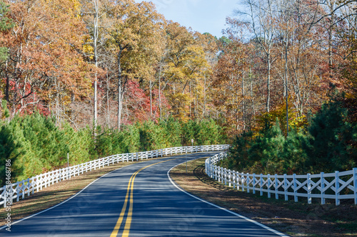 Photo: Road Curving Through Autumn Trees and White Fence Road Curving Through Autumn Trees and White Fence