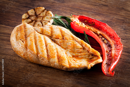 Photo: Grilled organic chicken with pepper and garlic on wood Grilled organic chicken with pepper and garlic on wood