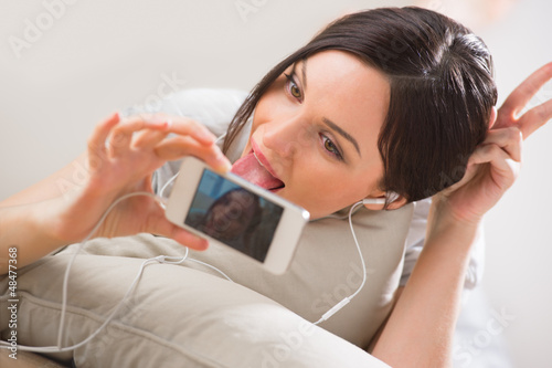 Photo: A young woman lying on the floor with her phone and shooting ( p A young woman lying on the floor with her phone and shooting ( p