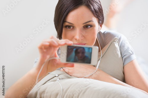 Photo: A young woman lying on the floor with her phone and shooting ( p A young woman lying on the floor with her phone and shooting ( p