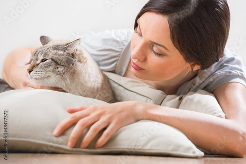 Photo: An attractive woman and her cat relaxing on pillows on floor at An attractive woman and her cat relaxing on pillows on floor at