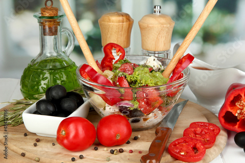 Photo: Fresh greek salad in glass bowl surrounded by ingredients for Fresh greek salad in glass bowl surrounded by ingredients for