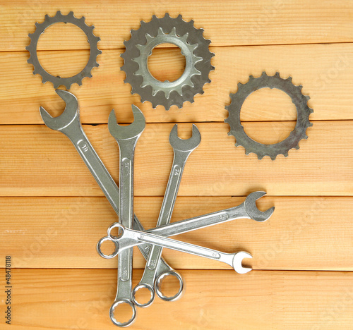 Photo: Metal cogwheels and spanners on wooden background Metal cogwheels and spanners on wooden background
