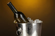 Bottle of wine in ice bucket on darck yellow background