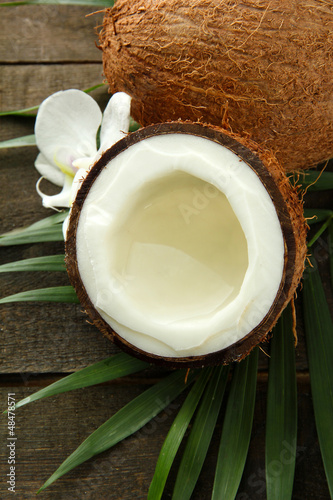 Photo: Coconut with leaves and flower, on grey wooden background Coconut with leaves and flower, on grey wooden background
