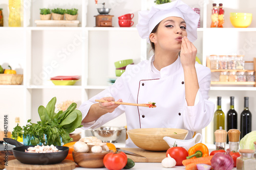 Photo: Young woman chef cooking in kitchen Young woman chef cooking in kitchen