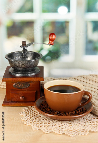 Photo: cup of coffee with scarf and coffee mill on table in room cup of coffee with scarf and coffee mill on table in room