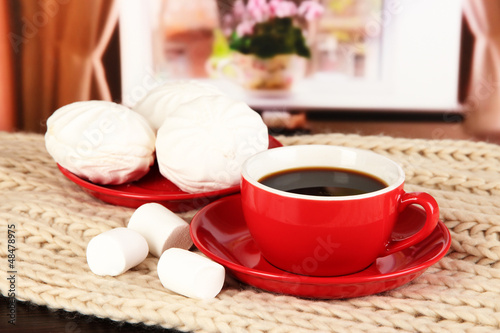 Photo: cup of coffee with scarf on table in room cup of coffee with scarf on table in room