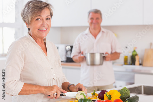 Photo: Old couple smiling preparing food Old couple smiling preparing food