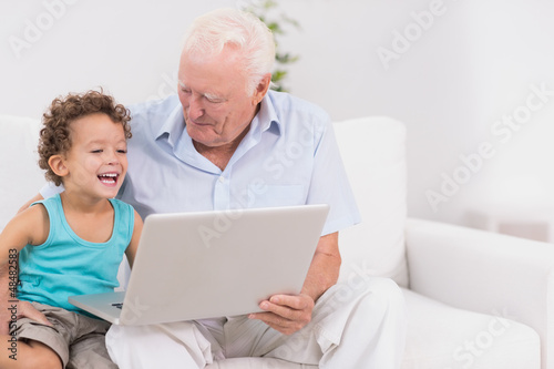 Photo: Grandfather and his grandson watching a laptop screen Grandfather and his grandson watching a laptop screen