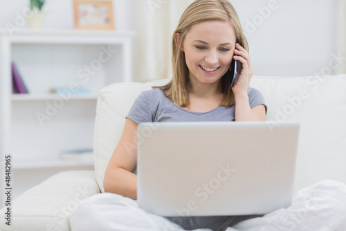 Photo: Casual woman using laptop and cellphone at home Casual woman using laptop and cellphone at home