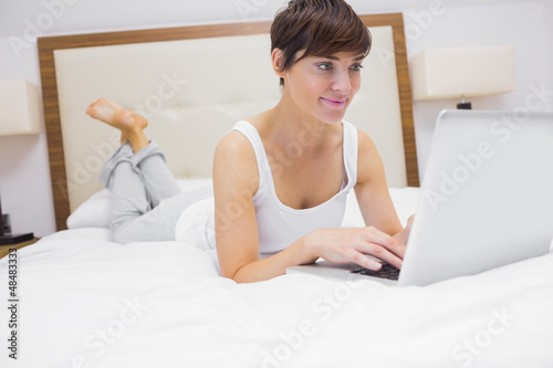 Photo: Woman lying on bed using laptop Woman lying on bed using laptop