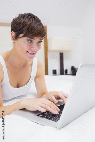 Photo: Pretty woman using laptop in bed Pretty woman using laptop in bed