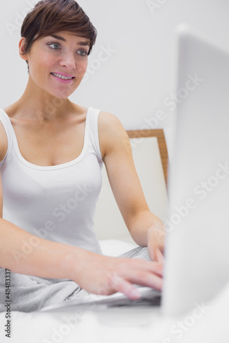 Photo: Woman in bed typing on laptop Woman in bed typing on laptop