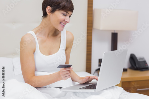 Photo: Woman shopping online in bed Woman shopping online in bed