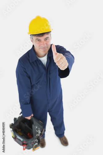 Photo: Mature man with tool bag showing thumbs up sign Mature man with tool bag showing thumbs up sign