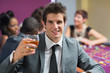 Man raising whiskey glass at roulette table