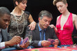 Man playing poker with two women beside him