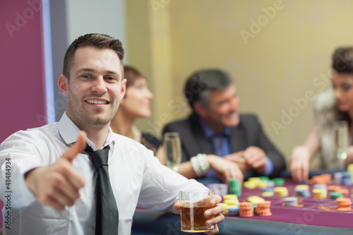 Photo: Man giving thumbs up and holding whiskey glass Man giving thumbs up and holding whiskey glass