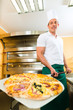 Photo: Man pushing the finished pizza from the oven Man pushing the finished pizza from the oven