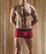 a muscular male torso on a background of the wooden wall