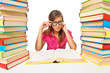 Photo: Woman student sitting at the desk surrounded with piles of books Woman student sitting at the desk surrounded with piles of books