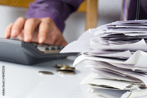 Photo: Bills in paper nail with hand calculating Bills in paper nail with hand calculating