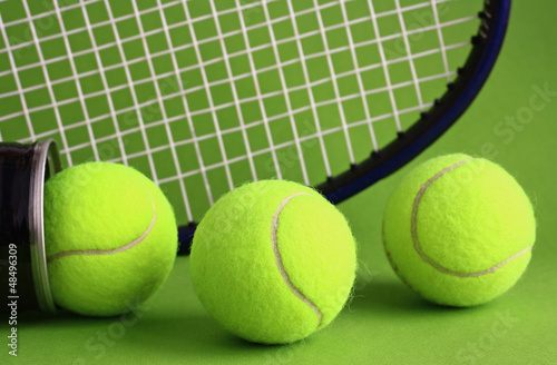 Photo: Tennis racket and ball on a green background. Tennis racket and ball on a green background.