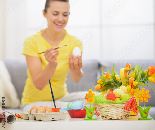 Photo: Closeup on table with Easter decoration and woman drawing on egg Closeup on table with Easter decoration and woman drawing on egg