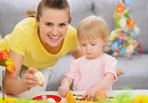 Photo: Happy mother and baby making Easter decorations Happy mother and baby making Easter decorations