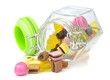 A glass jar of mixed sweets lying on a white background