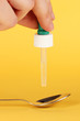 Medical droplet in spoon on yellow background