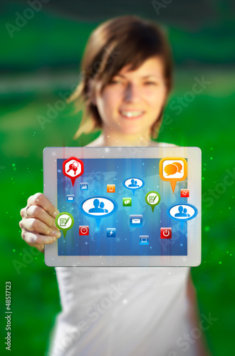 Photo: Young woman looking at modern tablet with abstract lights and so Young woman looking at modern tablet with abstract lights and so