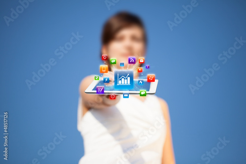 Photo: Young woman looking at modern tablet with abstract lights and va Young woman looking at modern tablet with abstract lights and va