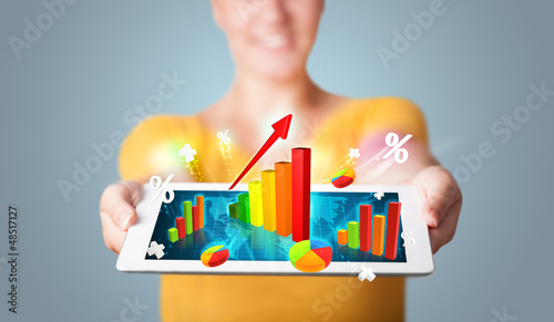 Photo: Young woman holding tablet with colorful graphs and diagrams Young woman holding tablet with colorful graphs and diagrams
